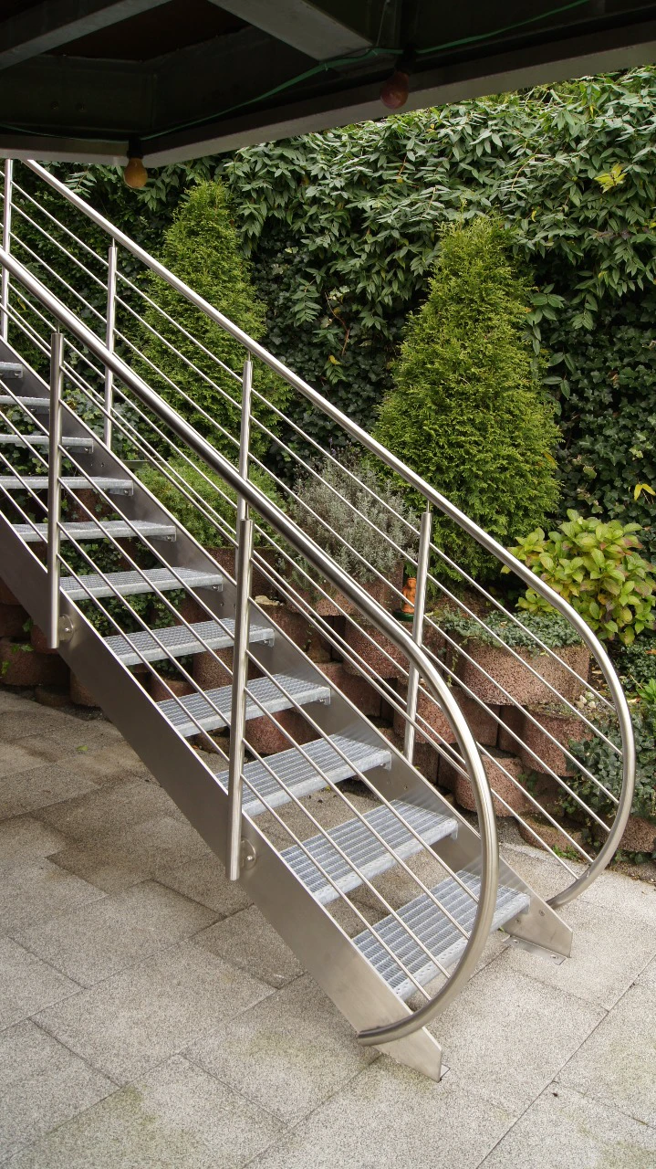 Stilvolle Außentreppe aus Edelstahl mit Gitterroststufen und geschwungenem Edelstahlgeländer