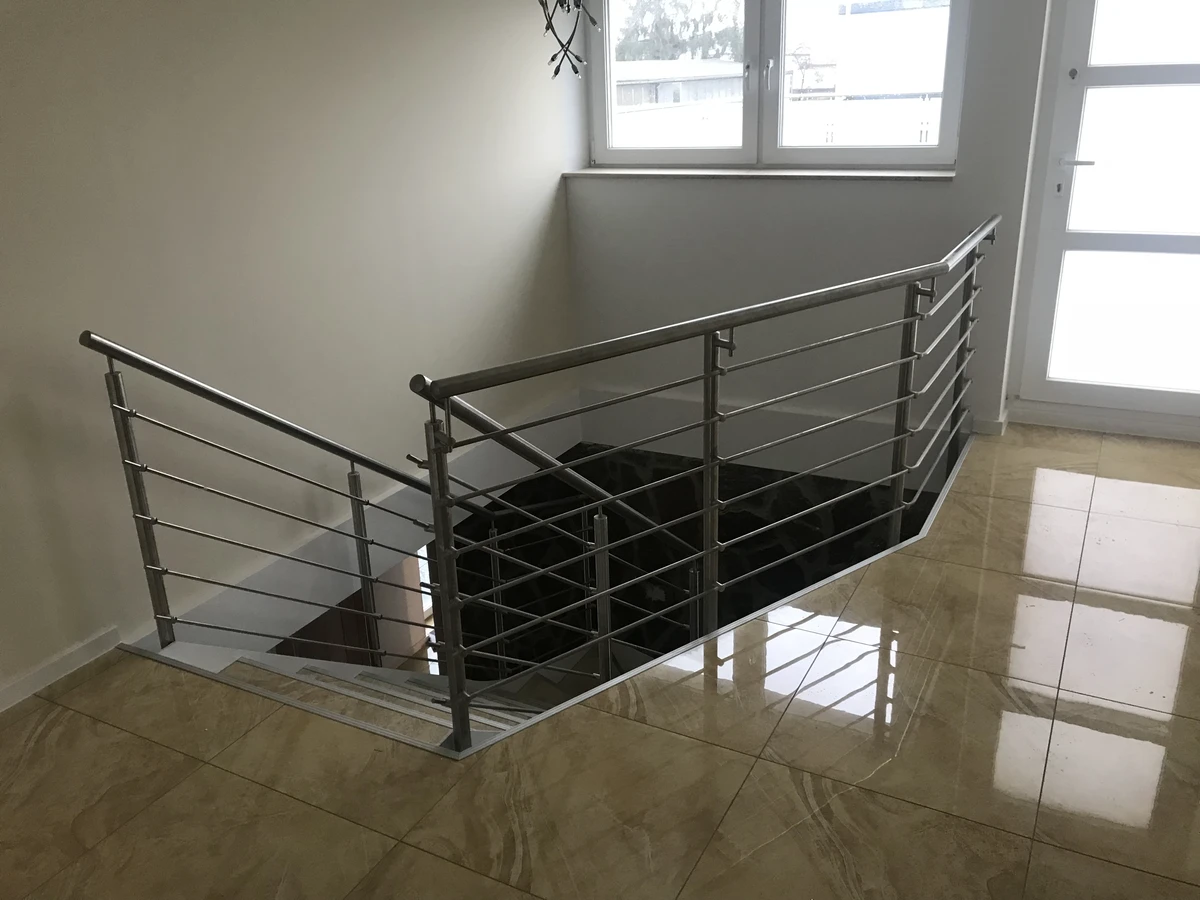 Moderne Innentreppe mit Edelstahlgeländer und glänzendem Fliesenboden