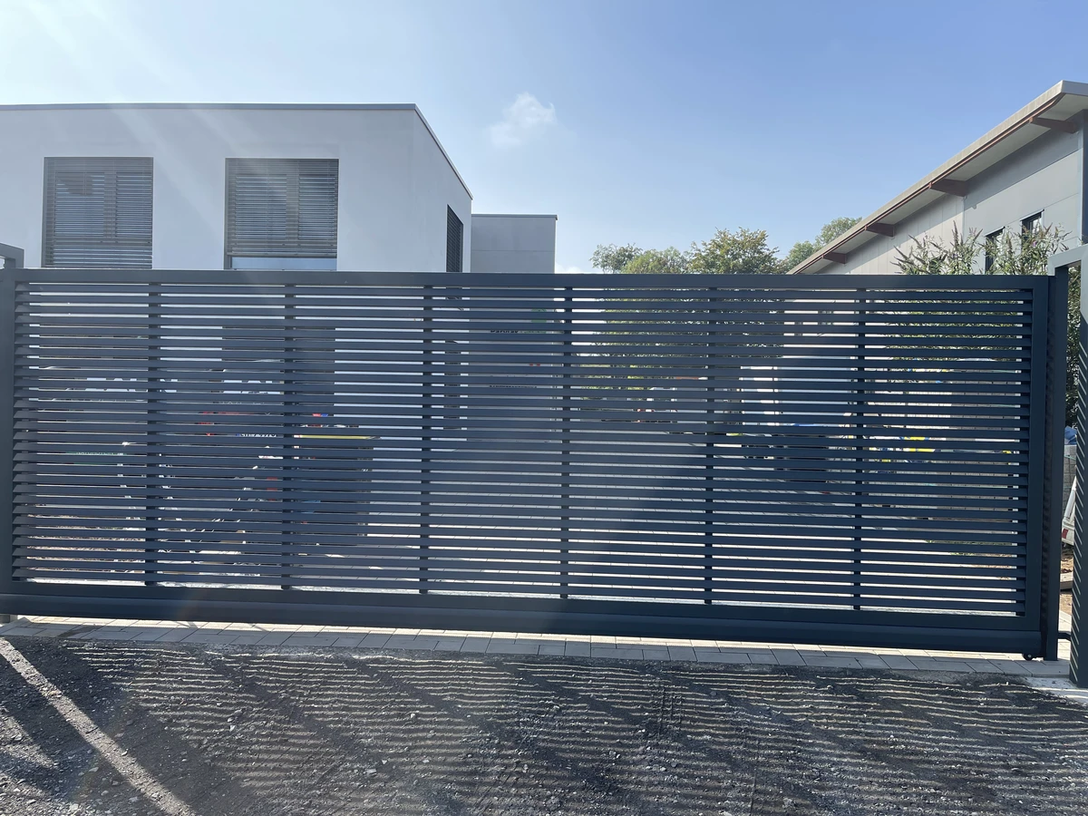 Schiebetore aus Metall mit schmalen horizontalen Lamellen vor moderner Hauszufahrt