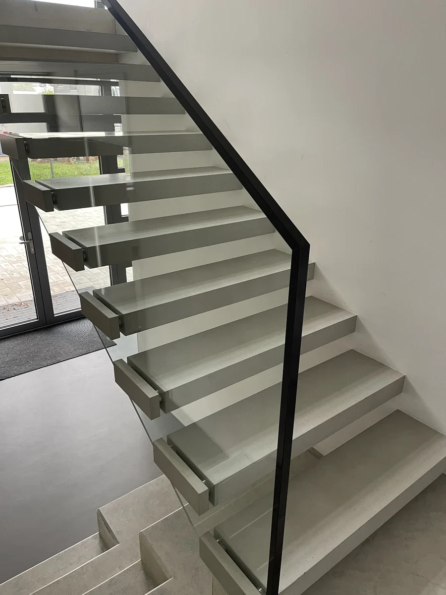 Schwebende Innentreppe als Bolzentreppe mit klarem Glasgeländer und Edelstahlbefestigungen