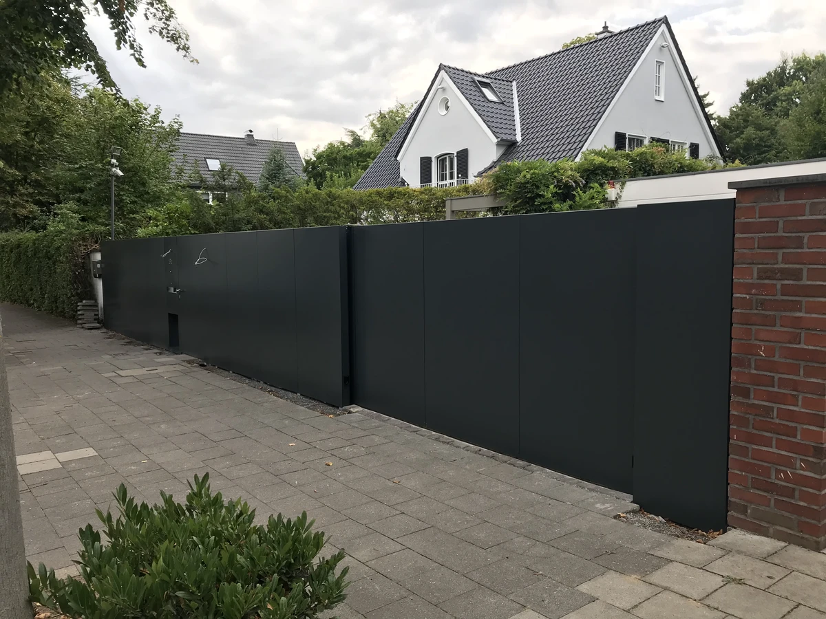 Schwarzes Metall-Schiebetor als moderne Toranlage vor Einfamilienhaus