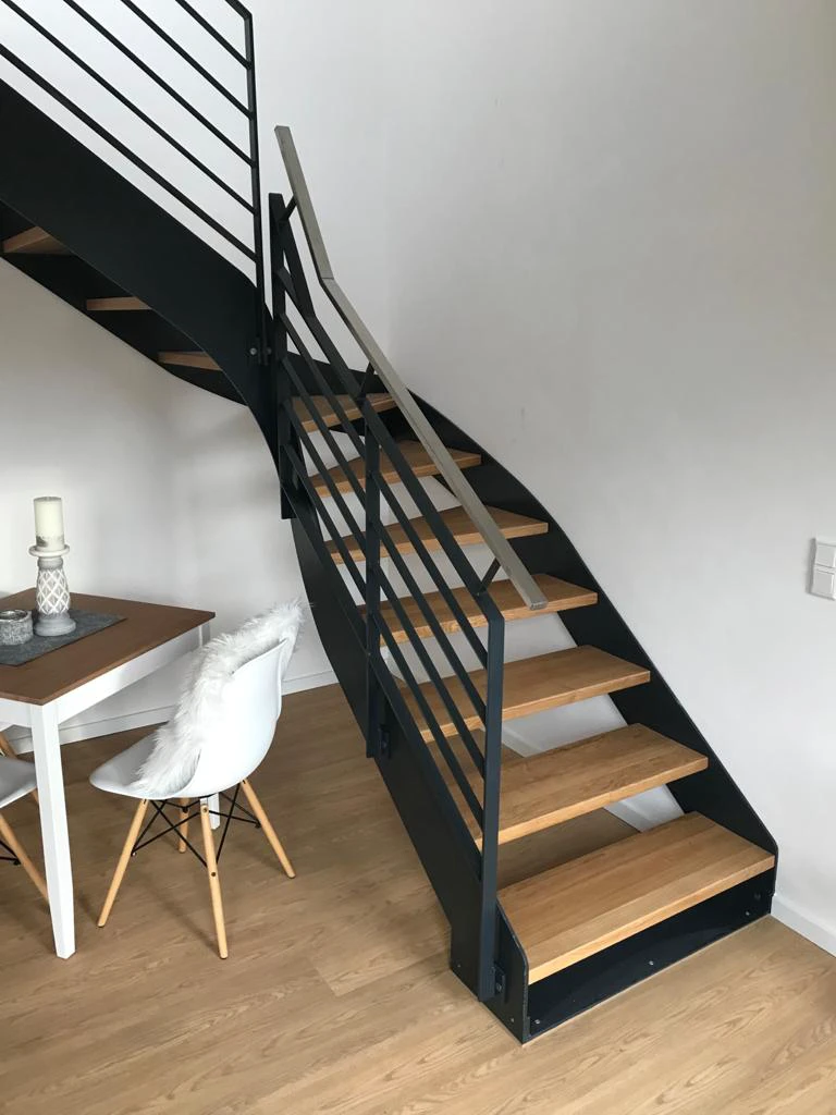 Moderne Innentreppe mit Metallwangen und freitragenden Holzstufen