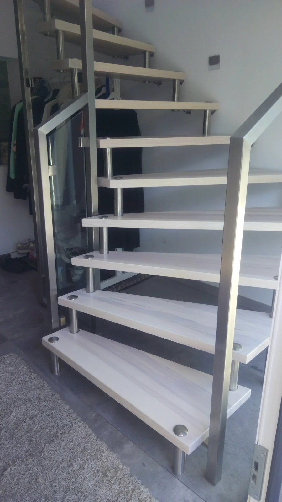 Moderne Innentreppe mit hellen Holzstufen, Edelstahlstützen und Glasgeländer in elegantem Design